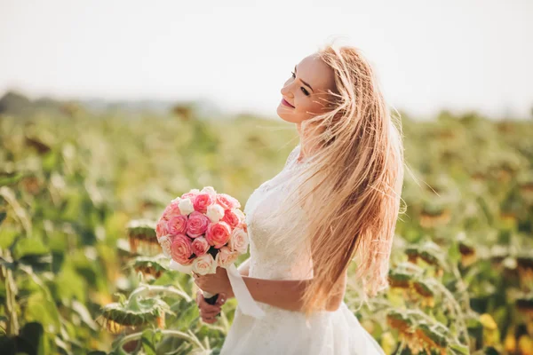 Noiva loira elegante com cabelos longos e um buquê de girassóis no campo — Fotografia de Stock