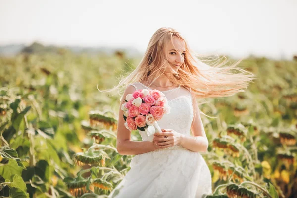 Elegant blonde bride with long hair and a bouquet of sunflowers in the field — Stock Photo, Image