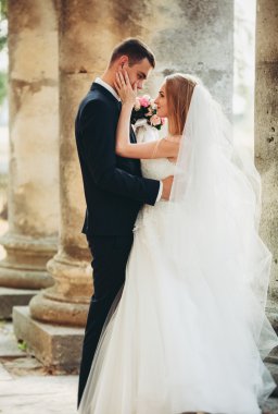 Güzel, romantik bir düğün. Yeni evliler. Eski kalenin yakınlarında sarılıyorlar.