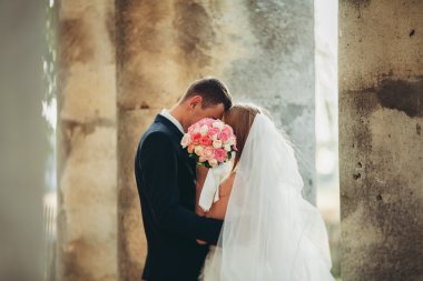 Güzel, romantik bir düğün. Yeni evliler. Eski kalenin yakınlarında sarılıyorlar.