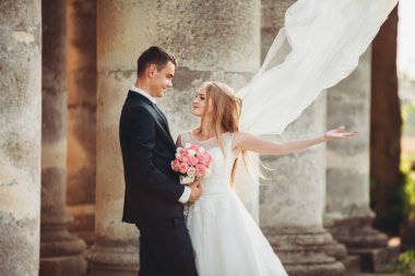 Güzel, romantik bir düğün. Yeni evliler. Eski kalenin yakınlarında sarılıyorlar.