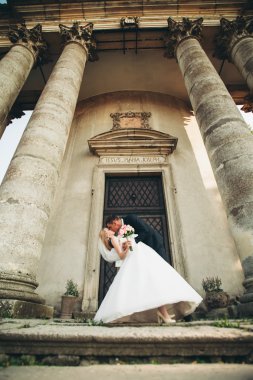 Güzel, romantik bir düğün. Yeni evliler. Eski kalenin yakınlarında sarılıyorlar.