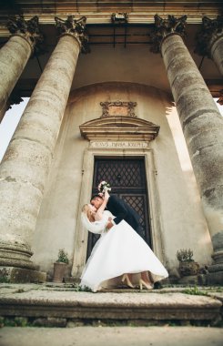 Güzel, romantik bir düğün. Yeni evliler. Eski kalenin yakınlarında sarılıyorlar.