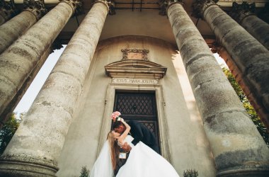 Güzel, romantik bir düğün. Yeni evliler. Eski kalenin yakınlarında sarılıyorlar.