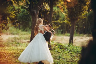 Güzel romantik bir çift yeni evliler gün batımında parkta sarılıyorlar.