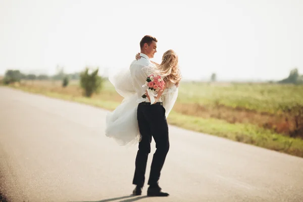 Hermosa pareja de boda, novia y novio posando en el camino — Foto de Stock