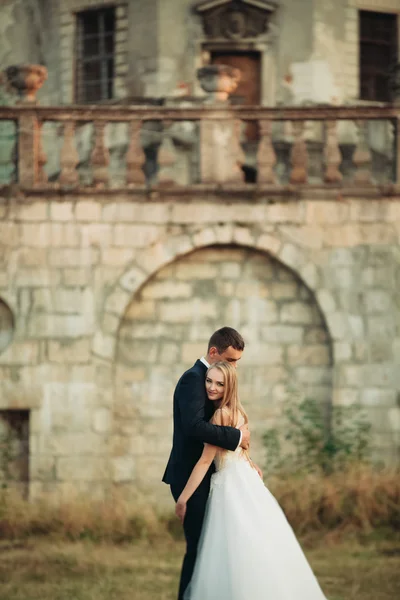 Beau couple de mariage romantique de jeunes mariés étreignant près du vieux château au coucher du soleil — Photo