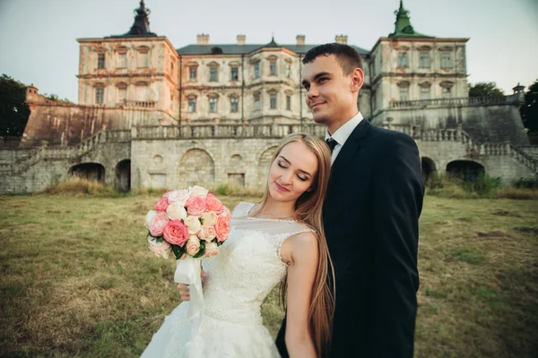 Casal romântico bonito do casamento, noivo e noiva abraçando perto do castelo velho no por do sol — Fotografia de Stock