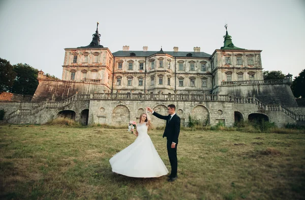 Krásné romantické svatební pár, ženich a nevěsta objímání poblíž starého hradu na západ slunce — Stock fotografie