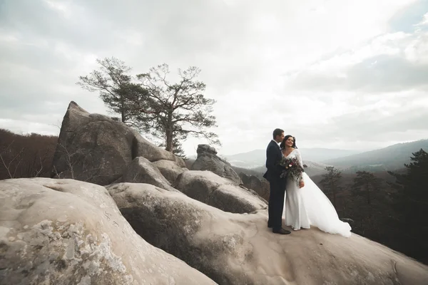 Πανέμορφη νύφη, γαμπρός φιλί και αγκαλιάζει κοντά στα βράχια με εκπληκτική θέα — Φωτογραφία Αρχείου