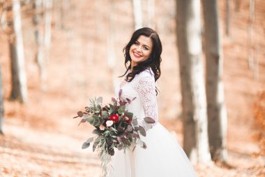 Orman ve göl poz buket tutan şık elbiseli güzel esmer gelin