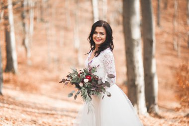 Orman ve göl poz buket tutan şık elbiseli güzel esmer gelin