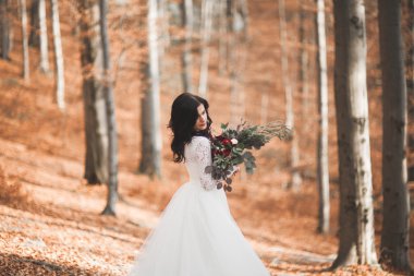 Orman ve göl poz buket tutan şık elbiseli güzel esmer gelin