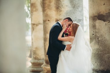 Güzel, romantik bir düğün. Yeni evliler. Eski kalenin yakınlarında sarılıyorlar.