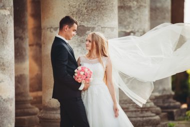 Güzel, romantik bir düğün. Yeni evliler. Eski kalenin yakınlarında sarılıyorlar.