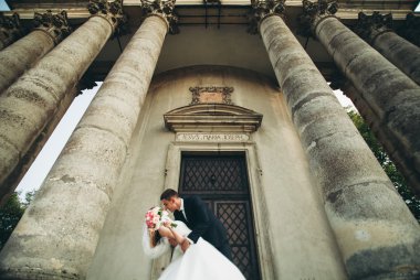 Güzel, romantik bir düğün. Yeni evliler. Eski kalenin yakınlarında sarılıyorlar.