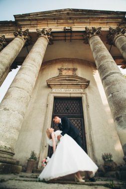 Güzel, romantik bir düğün. Yeni evliler. Eski kalenin yakınlarında sarılıyorlar.