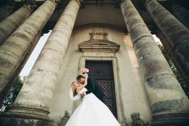 Güzel, romantik bir düğün. Yeni evliler. Eski kalenin yakınlarında sarılıyorlar.
