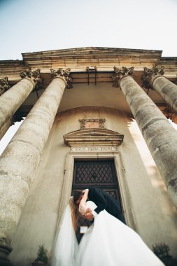 Güzel, romantik bir düğün. Yeni evliler. Eski kalenin yakınlarında sarılıyorlar.