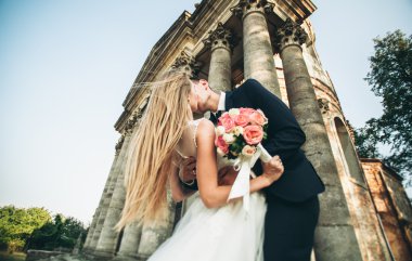 Güzel, romantik bir düğün. Yeni evliler. Eski kalenin yakınlarında sarılıyorlar.