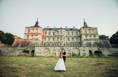 Güzel romantik Düğün çifti, damat ve gelin on sunset eski kale sarılma