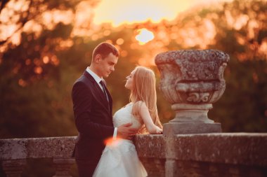 Güzel romantik Düğün çifti, damat ve gelin on sunset eski kale sarılma