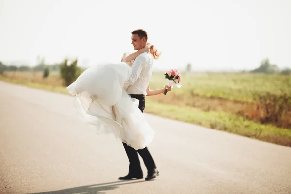 Красивая свадебная пара, невеста и жених позируют на дороге — стоковое фото