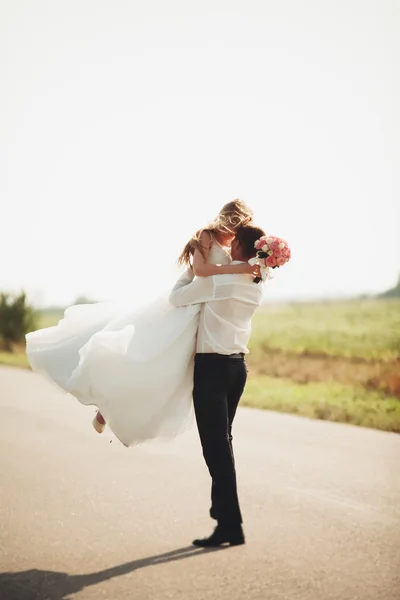 Vackra bröllopsparet, bruden och brudgummen poserar på väg — Stockfoto