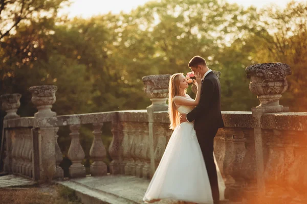 Casal romântico bonito casal de recém-casados abraçando perto do castelo velho no pôr do sol — Fotografia de Stock