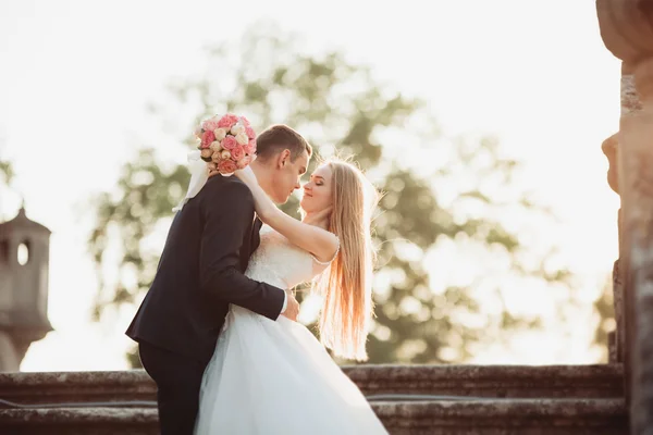 Mooie romantische bruidspaar van newlyweds knuffelen in de buurt van oude kasteel op de sunset — Stockfoto