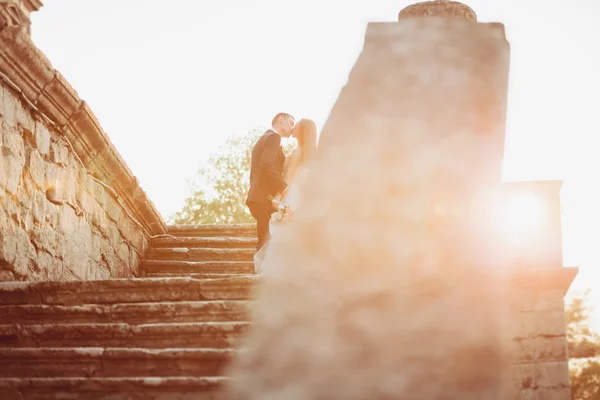 Όμορφο και ρομαντικό γάμο ζευγάρι των νεόνυμφων αγκάλιασμα κοντά στο παλιό κάστρο στο ηλιοβασίλεμα — Φωτογραφία Αρχείου