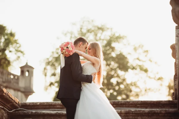 Casal romântico bonito casal de recém-casados abraçando perto do castelo velho no pôr do sol — Fotografia de Stock