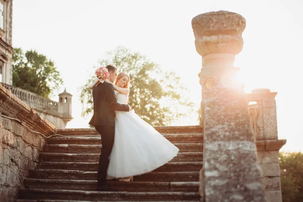 Bella coppia di sposi romantici che si abbracciano vicino al vecchio castello al tramonto — Foto Stock