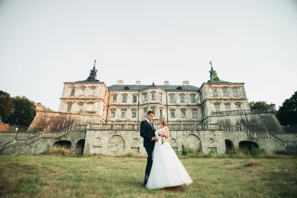 Beau couple de mariage romantique, marié et mariée étreignant près du vieux château au coucher du soleil — Photo