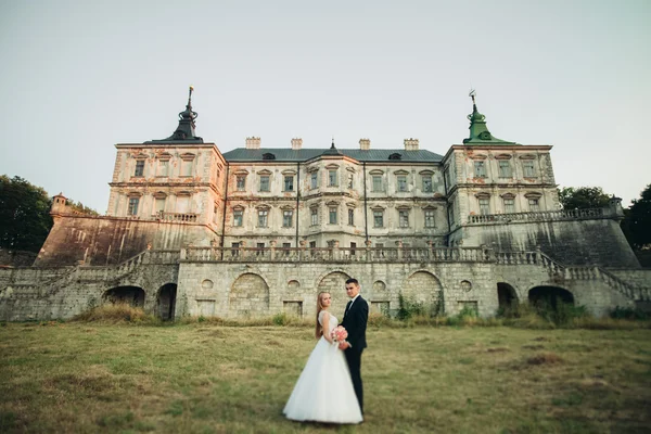 Beau couple de mariage romantique, marié et mariée étreignant près du vieux château au coucher du soleil — Photo