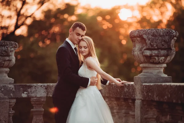 Güzel romantik Düğün çifti, damat ve gelin on sunset eski kale sarılma