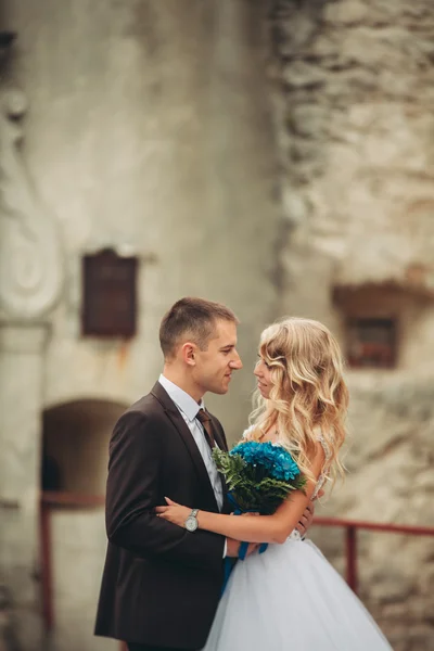 Boldog esküvői pár átölelve hoznak, és mosolyogva egymást a háttérben a régi kastély — Stock Fotó