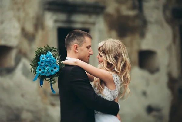 Feliz casamento casal abraçando e sorrindo uns aos outros no fundo velho castelo — Fotografia de Stock