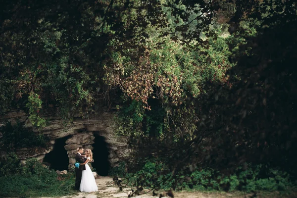 Pareja de boda de lujo abrazos y besos en el fondo hermosas plantas, cueva cerca del antiguo castillo —  Fotos de Stock