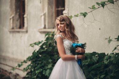 Gelin buketi pozlar arka plan güzel bitkiler üzerinde lüks genç sarışın gelinle