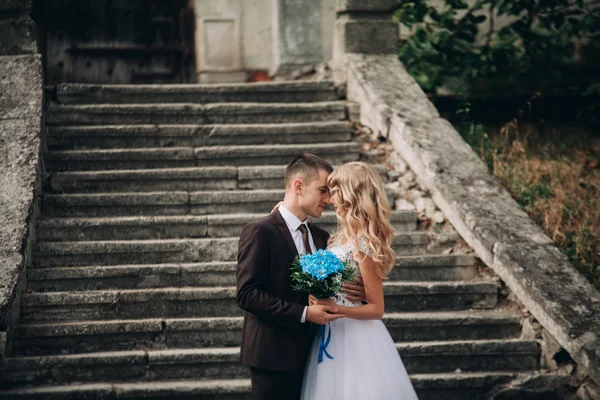 Luxury wedding couple hugging and smiling each other on the stairs in castle