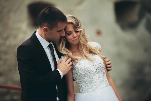 Feliz casamento casal abraçando e sorrindo uns aos outros no fundo velho castelo — Fotografia de Stock