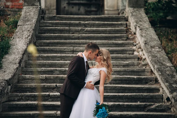Luxus-Hochzeitspaar umarmt und lächelt einander auf der Treppe im Schloss — Stockfoto
