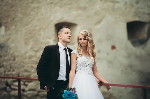 Feliz boda pareja abrazándose y sonriendo el uno al otro en el fondo viejo castillo — Foto de Stock