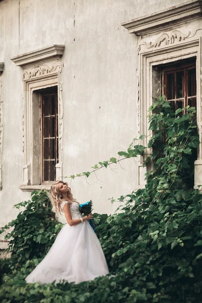 Роскошная молодая блондинка невеста с свадебным букет позы на заднем плане великолепные растения — стоковое фото