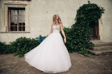 Güzel genç sarışın gelin gelin buketi arka plan güzel bitkiler üzerinde dans ile