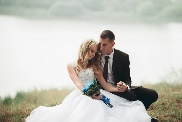 Ευτυχισμένος γάμος ζευγάρι που κάθεται στο έδαφος κοντά στη λίμνη — Φωτογραφία Αρχείου