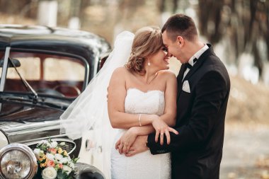 Şık düğün çift, Gelin, damat öpüşme ve retro arabanın yakınında sonbaharda sarılma