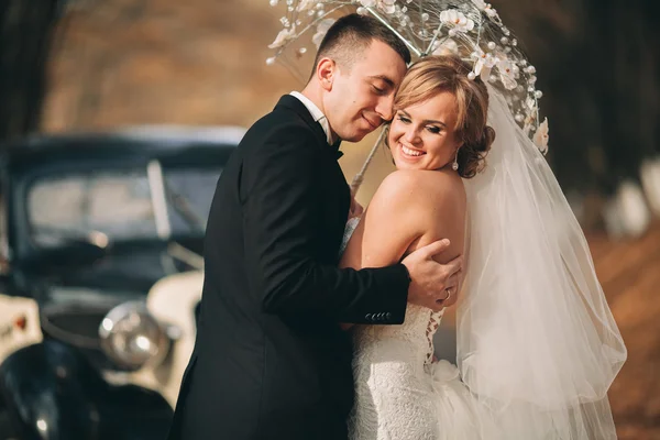 Stylish wedding couple, bride, groom kissing and hugging near retro car in autumn — Stock Photo, Image