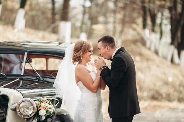 Elegante pareja de boda, novia, novio besándose y abrazándose cerca de coche retro en otoño — Foto de Stock